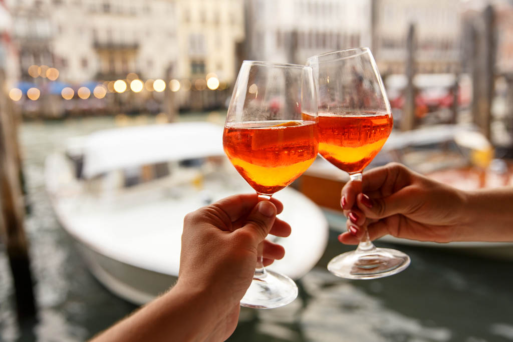 Couple clinking glasses with aperol spritz in Venice, Italy