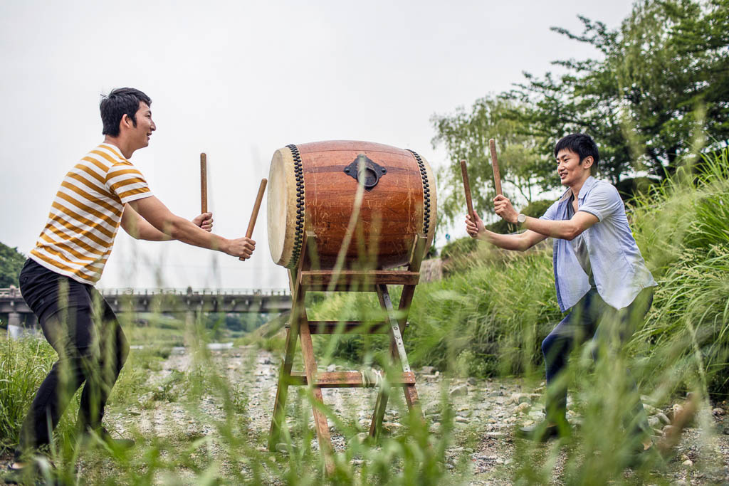 Outdoor shot of two young men playing japanese taiko drum