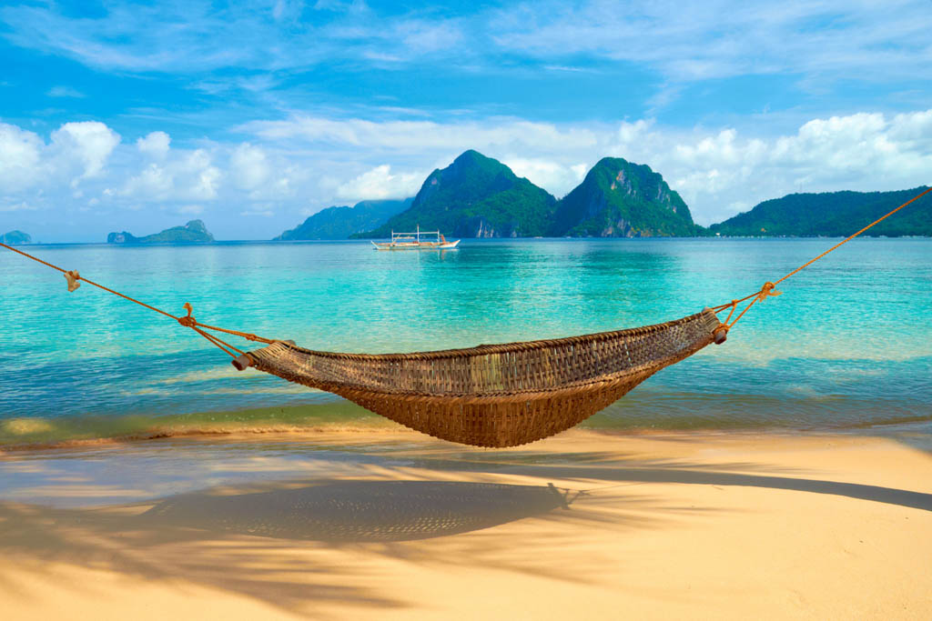 A hammock at the beach with the view of Bacuit Archipelago islands - El Nido, Philippines
