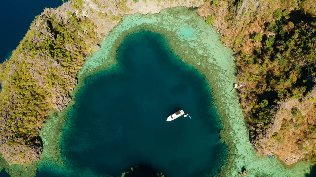 Aerial drone speed boat with tourists in beautiful lagoon. tropical landscape. blue lagoon surrounded by rocks on tropical island. Seascape, tropical landscape. Palawan, Philippines, Busuanga