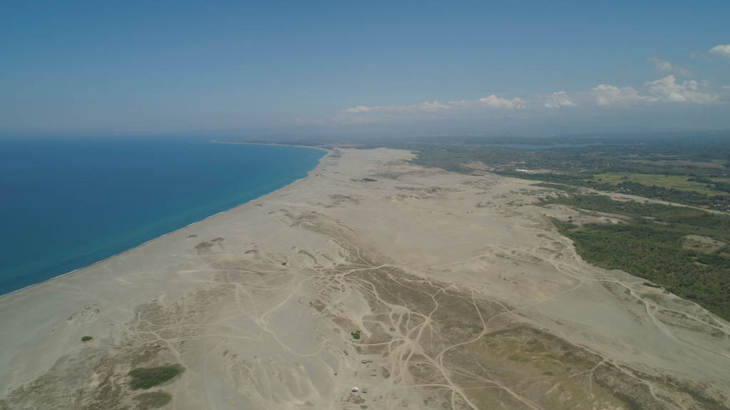 Aerial view of beautiful lonely beach and Paoay sand dune. Philippines, Luzon. Sand dunes near to the sea with sky. Ilocos Norte.