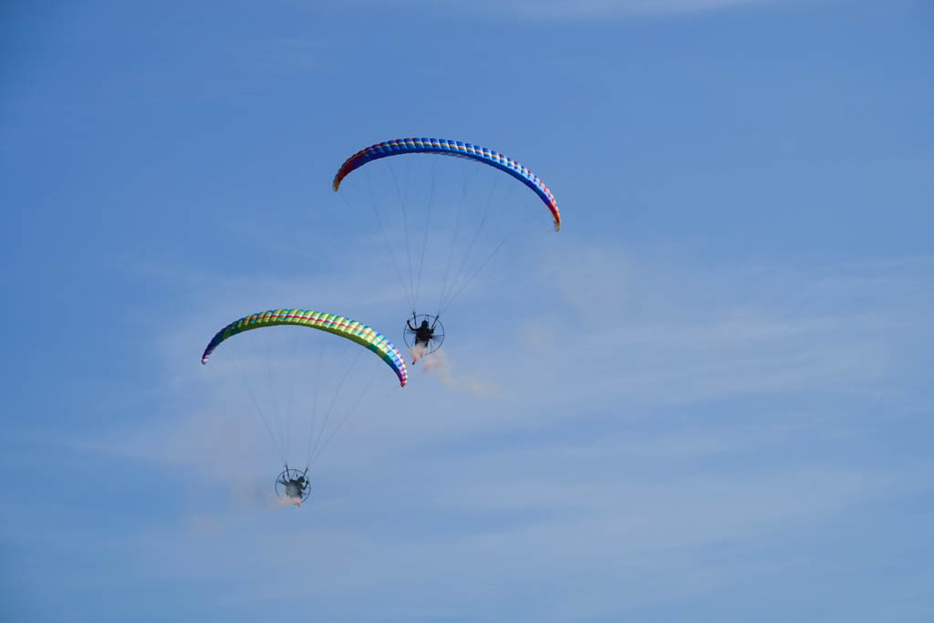 Hot air balloon festival features flying paragliders doing rounds for an admiring audience, Carmona, Philippines