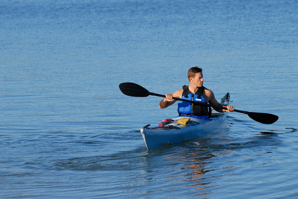 An athletic man is backing off the shore into calm blue waters of Mission Bay, San Diego, California. Copy space on top and left. (An athletic man is backing off the shore into calm blue waters of Mission Bay, San Diego, California. Copy space on top