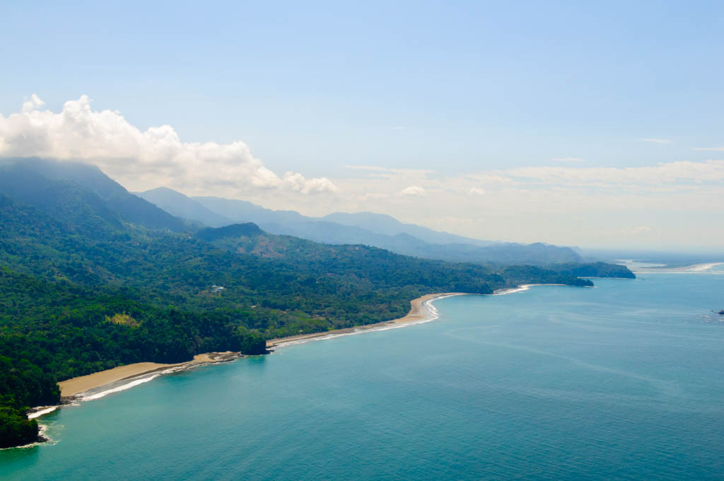 Vibrant tropical forests flow down from the mountains to the sandy beaches along the coast. Aerial view of the Costa Ballena near Dominical, Costa Rica.