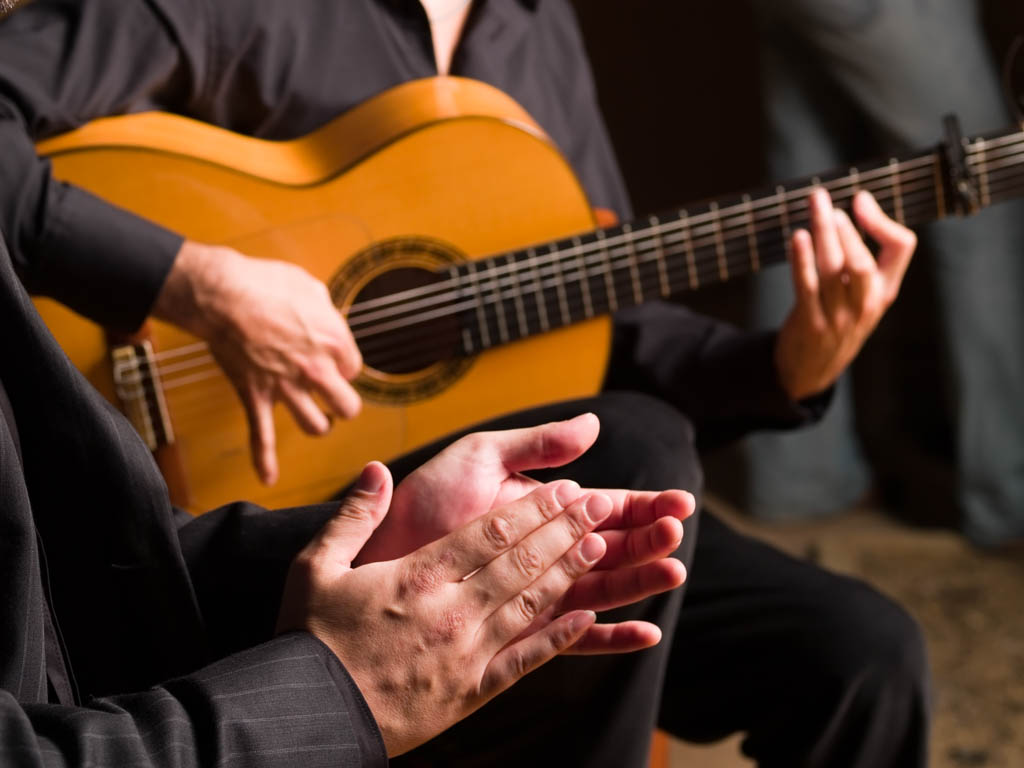 Close-up of flamenco guitar and hands clapping