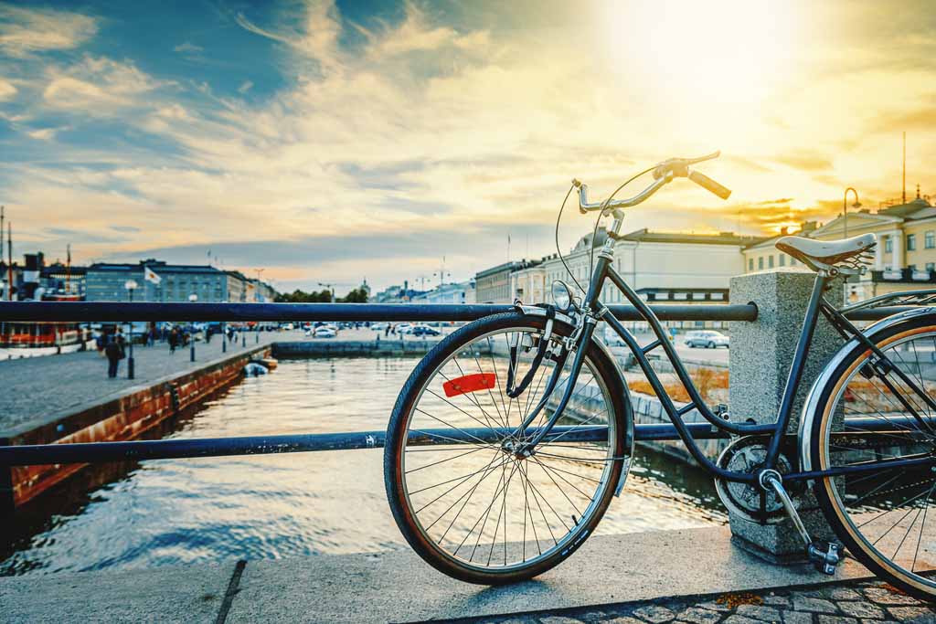 Black retro bicycle parked on the waterfront of Helsinki, the capital of Finland, against the backdrop of the city and sunset