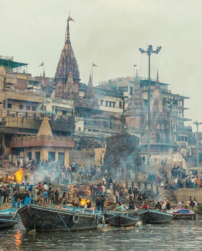 Crowd on Burning Ghat on the riverbank of Ganges. View from the river. Varanasi known as Banaras is the holies city in India. It is on the banks of the river Ganges where the special funeral ritual, cremation goes on for purifying and final releases of the spirit from the body.