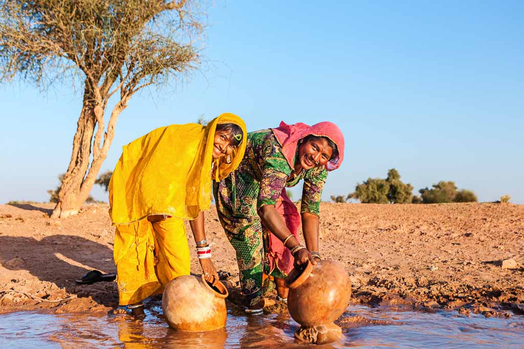 Indian women collecting water from the lake. Collecting and carrying water are women's responsibilities in India. Rajasthani women often walk long distances through the desert to bring back jugs of water that they carry on their heads . Thar Desert, Rajasthan. India.