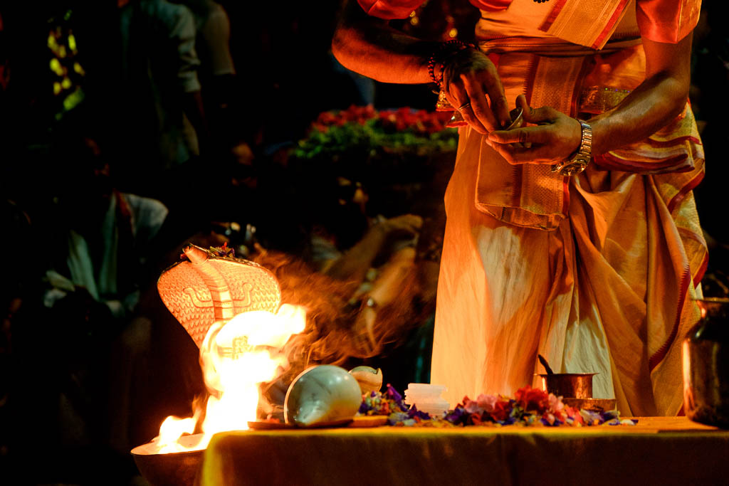 close up of young hindu priest performing daily ritual ganga aarti ceremony with fire and symbolic snake