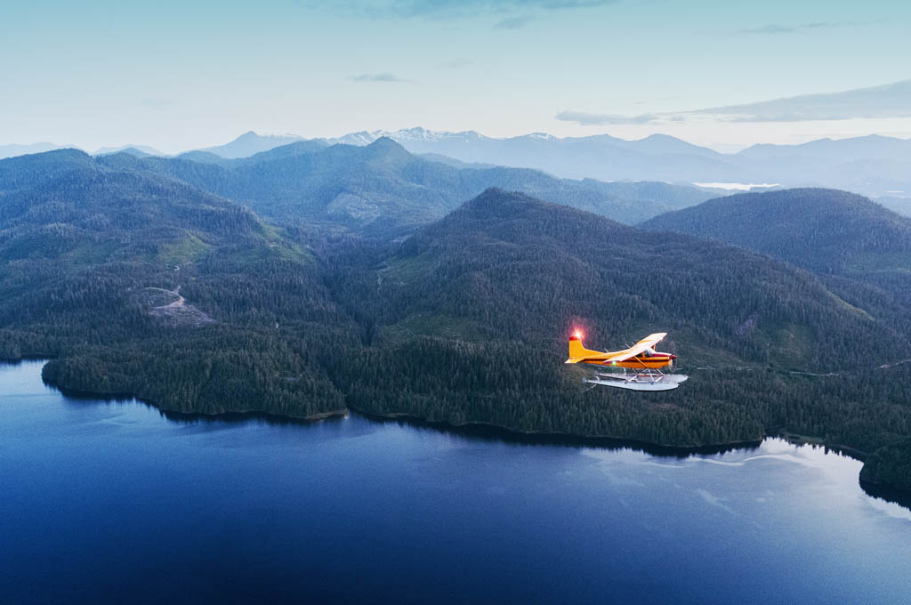 A seaplane flies over Southern Alaska in twilight. Shot at high iso with slight grain.