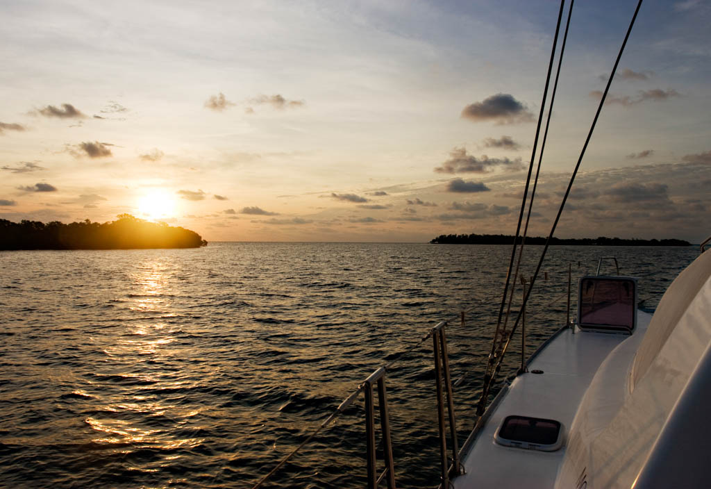 Boat sailing at sunrise between islands. Caribbean Dawn. Crawl Caye, Belize.