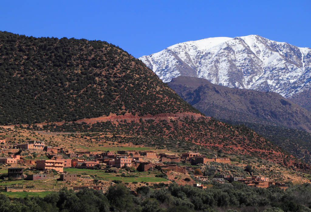 Snowcapped peaks and fertile valley with a small village built of adobe, High Atlas Mountain range in the Toubkal National Park. Toubkal is the highest mountain in North Africa. Marrakesh district, Morocco.