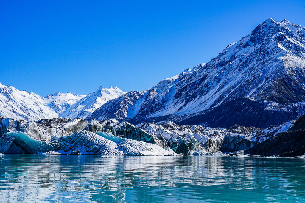 Beautiful Turquoise Blue Icebergs with A Water Reflection on Tasman Glacier Terminal Lake with the Snowcapped Mountain Background in Aoraki Mount Cook National Park, South Island, New Zealand