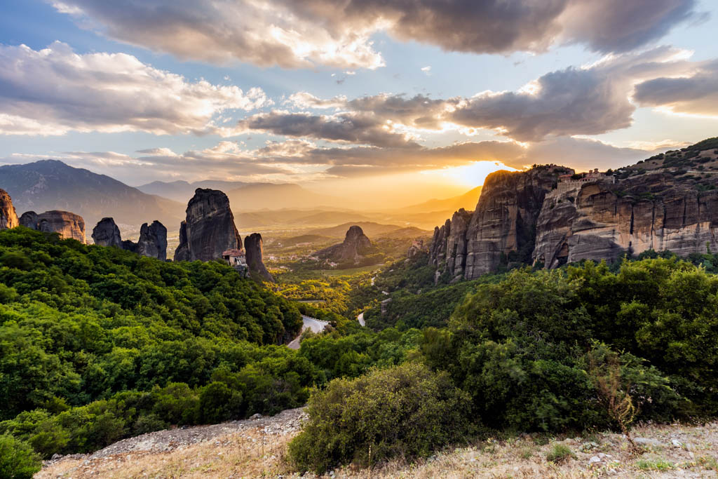 Monastery Meteora Greece. Stunning summer panoramic landscape. View at mountains and green forest against epic blue sky with clouds. UNESCO heritage list object.