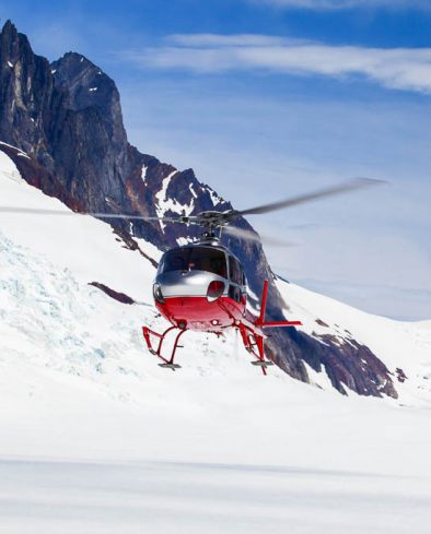 A helicopter landing on a remote mountain glacier.