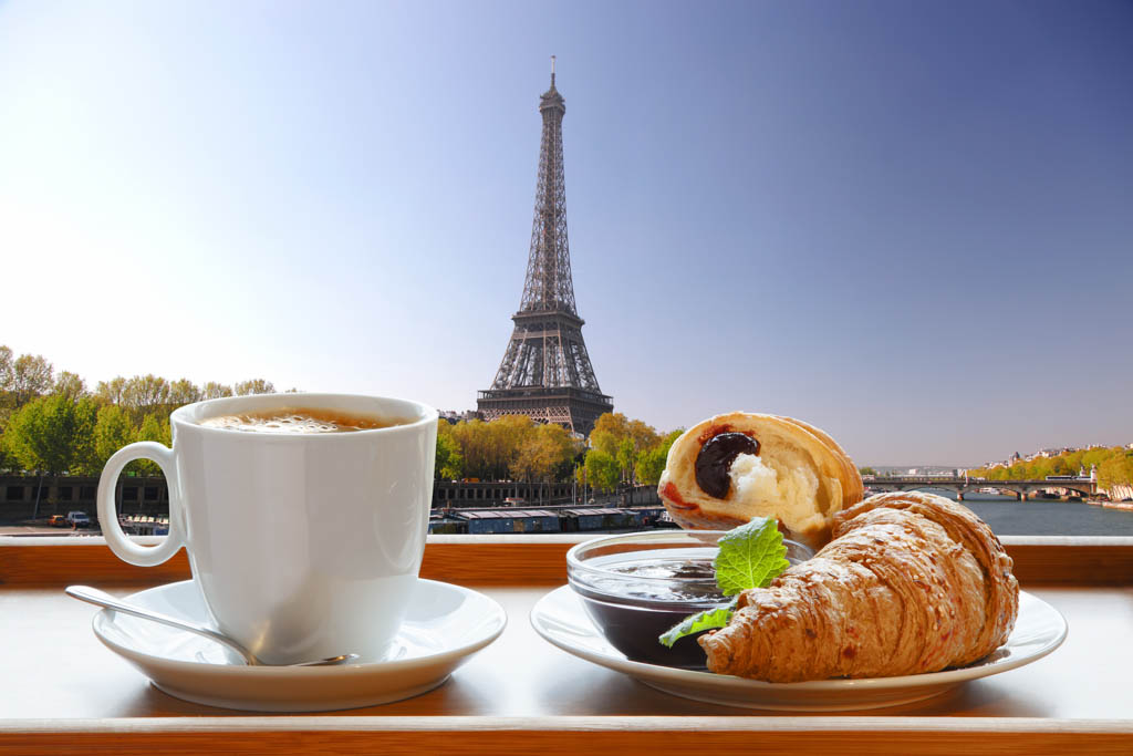 Cup of coffee with croissants and strawberry jam against Eiffel Tower in Paris, France