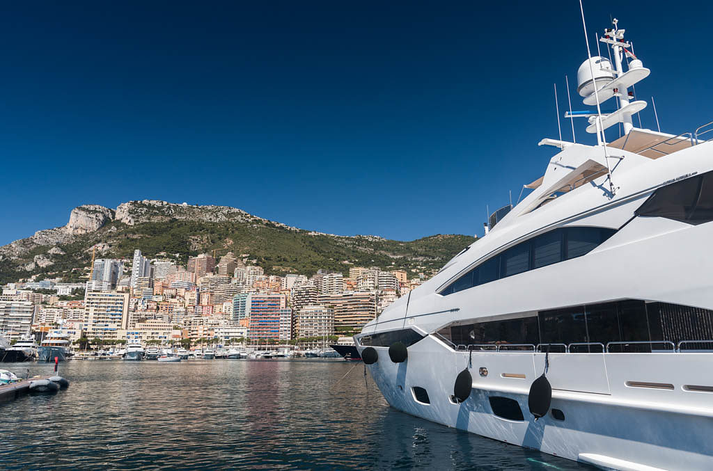 Luxury yachts berthed in the Port Hercules harbour of Monaco Monte Carlo. In the background overlooking the harbour are the many high rise luxury apartment buildings climbing the hillside
